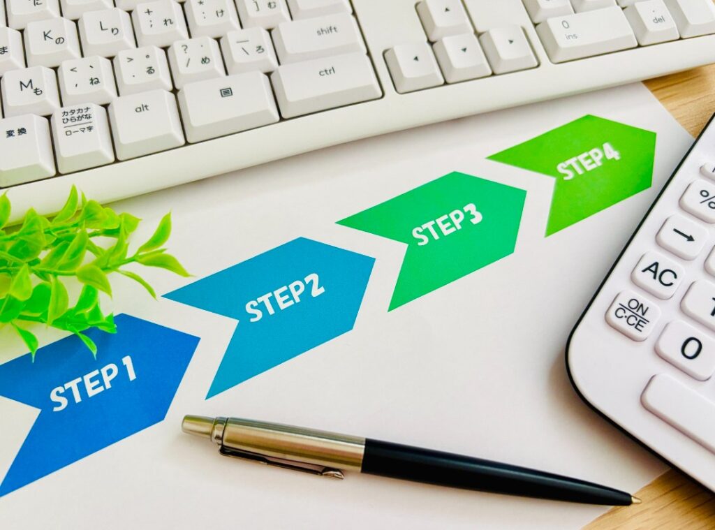 デスクに置かれた白い電卓とクリップボード。貸しオフィスの初期費用や月額料金、ランニングコストをシミュレーションしているイメージ。